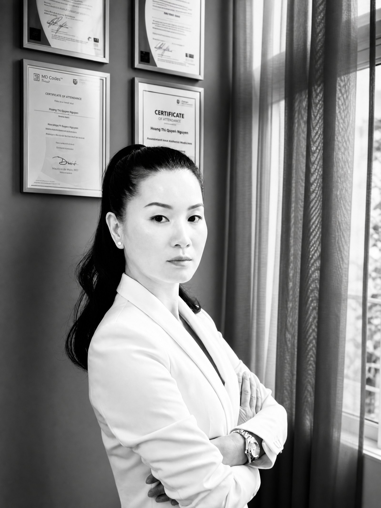 Dr Q Nguyen foran klinikkens certifikater